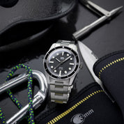 Orologio HTD Aquatic diver in acciaio con quadrante nero, posato tra attrezzatura subacquea con corda, coltello e muta.