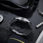 Vista laterale del bracciale e della chiusura logata HTD dell’orologio Aquatic Spaceboy, appoggiato su superficie bagnata con attrezzatura da immersione.