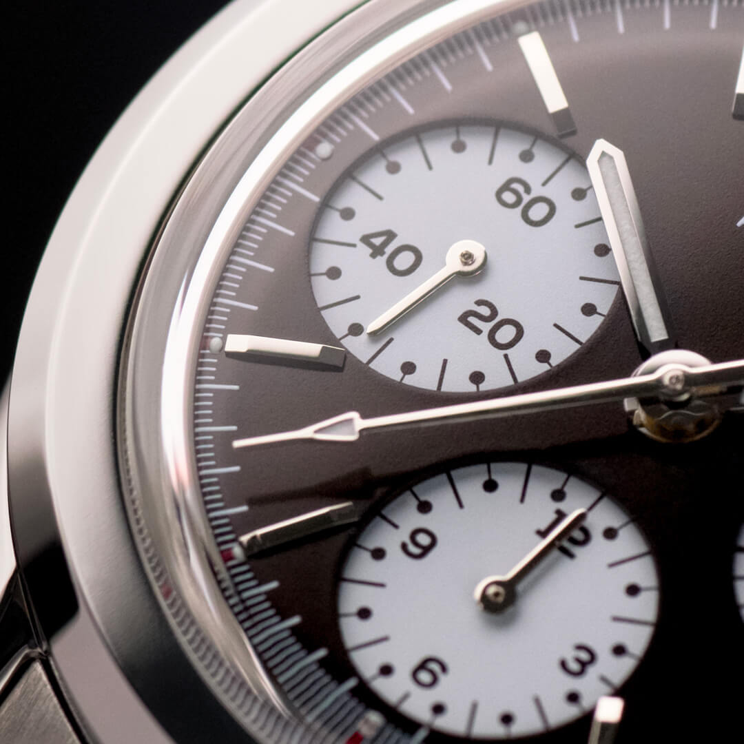 Macro del quadrante di un orologio cronografo con sfondo nero e tre contatori bianchi a contrasto.