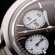 Macro del quadrante di un orologio cronografo con sfondo nero e tre contatori bianchi a contrasto.