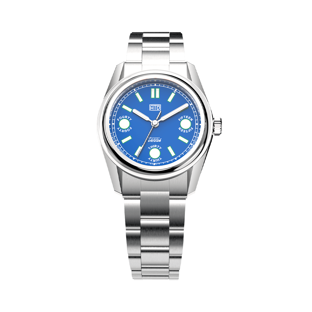 Orologio HTD Tennis Cemento con quadrante blu e dettagli ispirati al punteggio del tennis, fotografato frontalmente con bracciale in acciaio.