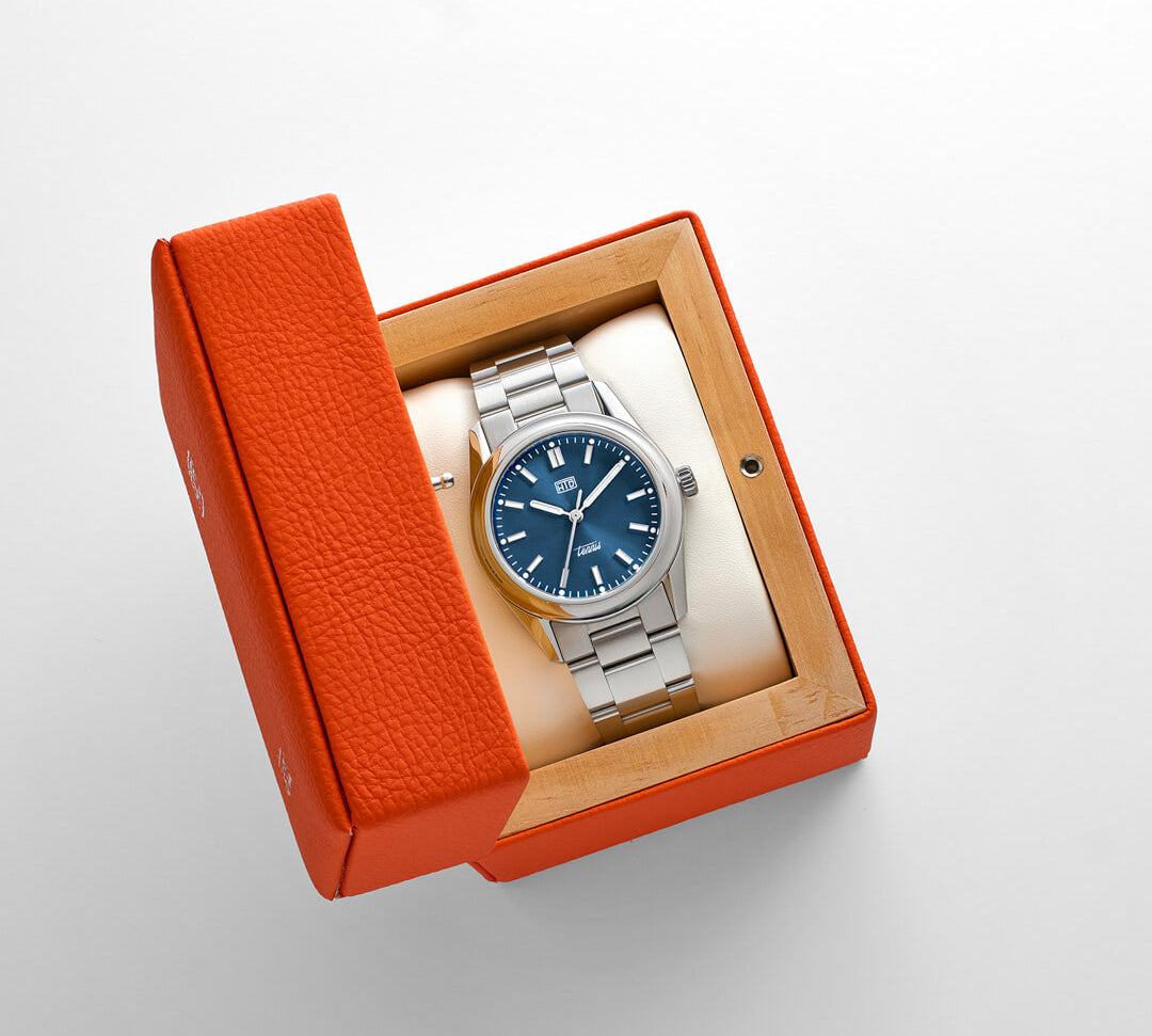 Orologio HTD Tennis Chic nella sua scatola arancione, con quadrante blu acceso e bracciale in acciaio.