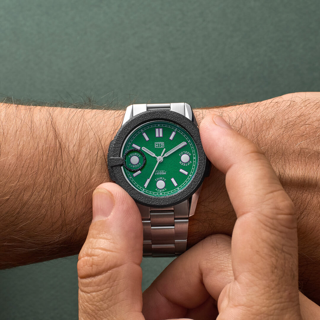 Orologio HTD Tennis Erba indossato al polso con protezione in gomma nera sul quadrante verde, bracciale in acciaio.